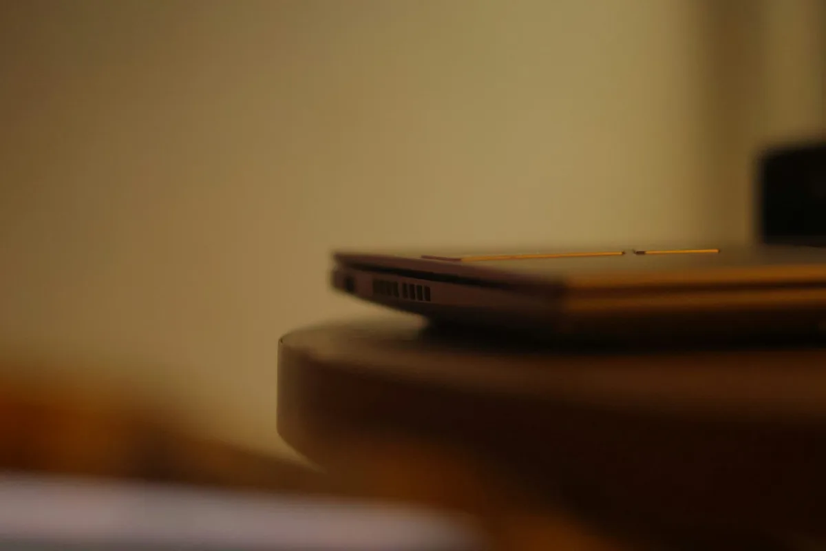 Illustrative stock photo of a closed laptop on a wooden table in warm, softly focused light.