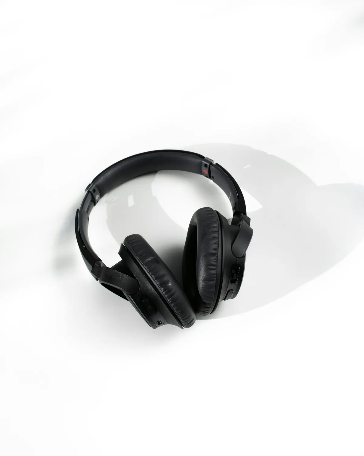 Illustrative stock photo of black over-ear headphones resting on a white surface.